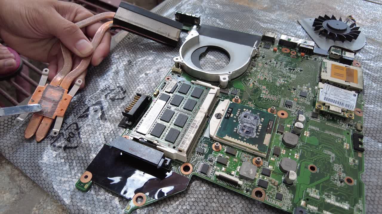 Replacing the thermal paste of an old laptop motherboard by scraping it off first from the heatsink and placing it with a new one