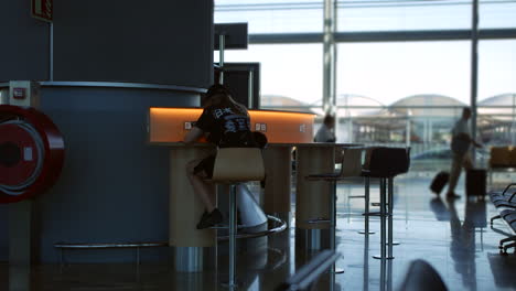 a teenage girl using a phone charging station at an airport