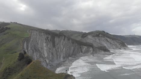 aerial drone shot of a man over a cliff