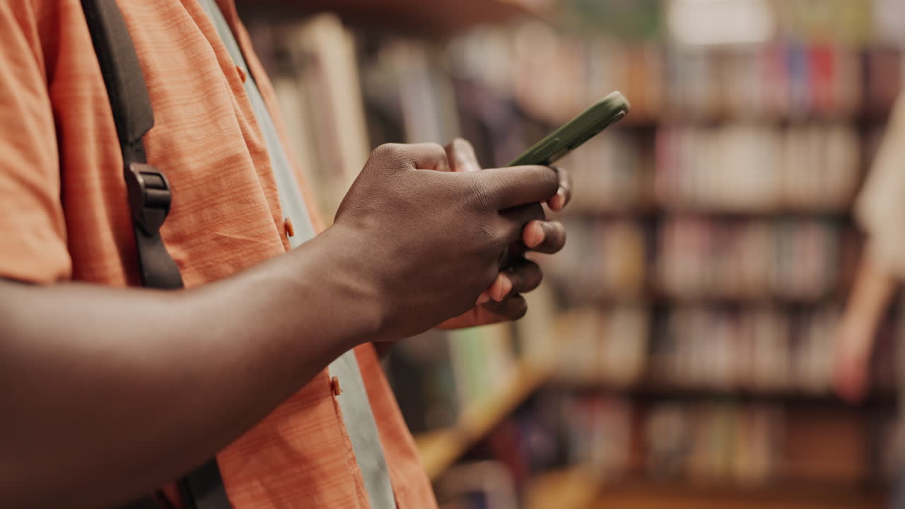 Persona che usa il telefono cellulare in una libreria