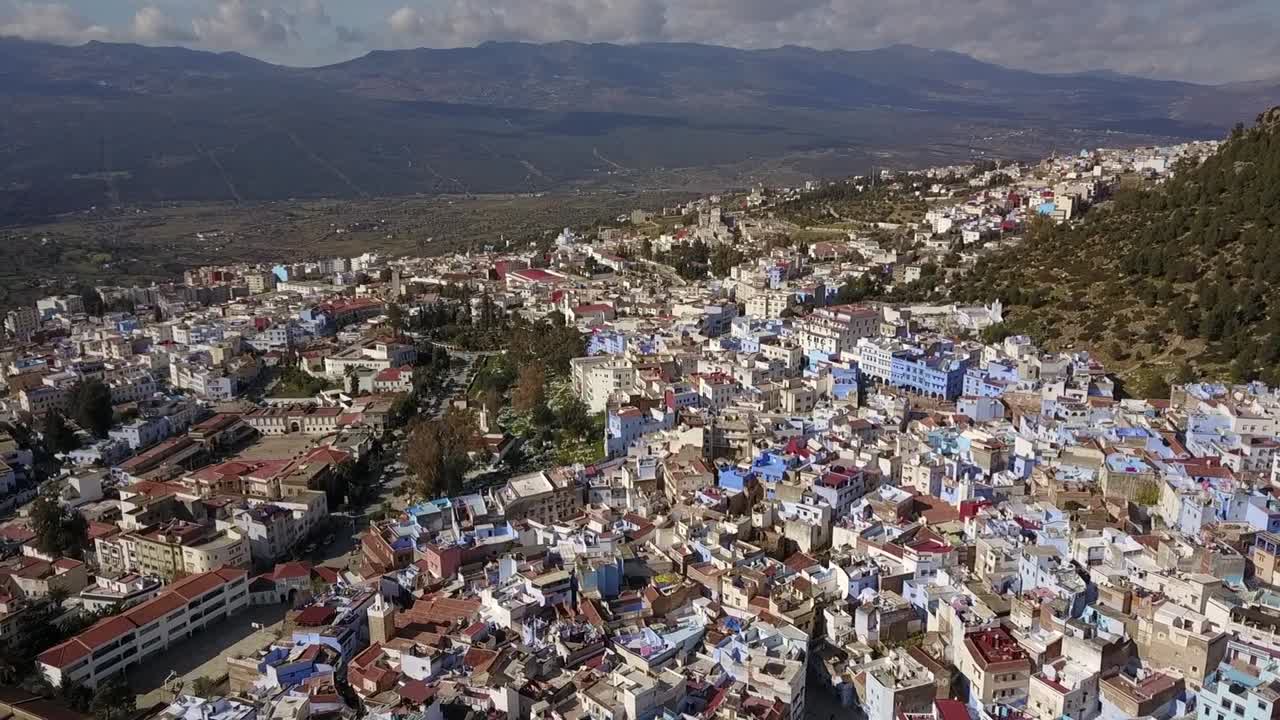 Deslumbrante panorama aéreo amplo em HD de Chefchaouen, a Cidade Azul. Captura os icónicos edifícios azuis contra as escarpadas Montanhas do Rife. Perfeito para documentários de viagem e cultura.