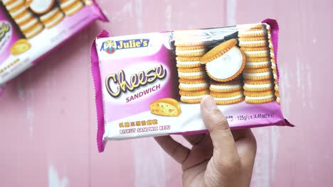 la mano sosteniendo un paquete de galletas de sándwich de queso de julie