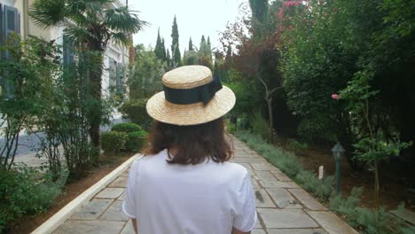 tourist woman walking on green summer park back view. young woman in city park