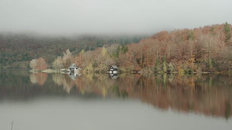 Reflexion-Des-Bohinjer-Sees-Während-Der-Herbstsaison-Mit-Erstaunlichen-Orangefarbenen-Herbstfarben-Mit-Einer-Bootshütte-Am-Seerand