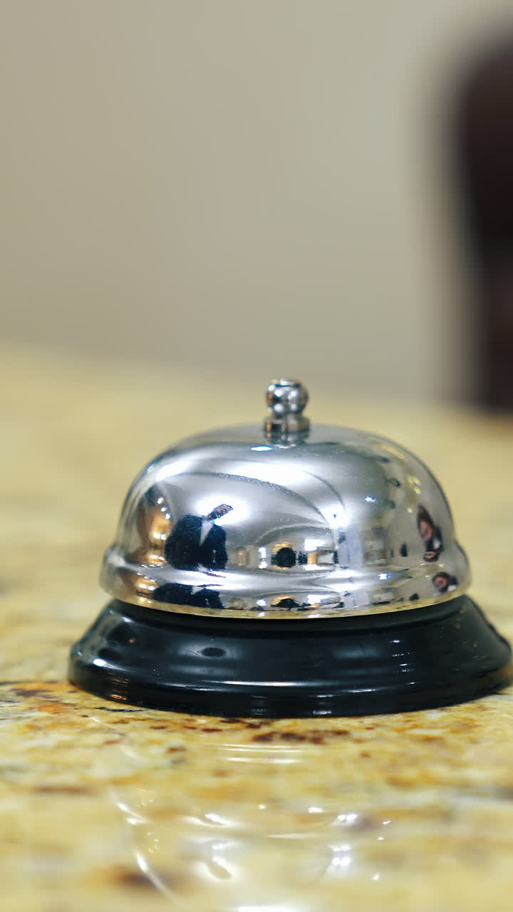 Metal bell button at hotel. Hand touching the electronic bell on the table to call a receptionist at a hotel. Close-up. Vertical video