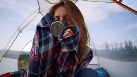 Female-hiker-drinking-tea-from-mug-in-tent