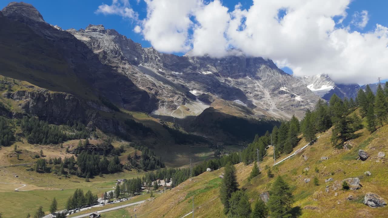 Rising up aerial drone view of pine trees and mountains in Valtournenche, Aosta Valley, Valle d’Aosta, showing the alpine landscape