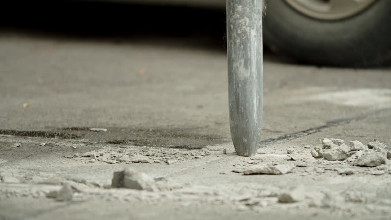 Close-up of excavator hydraulic arm rock breaker working on concrete road