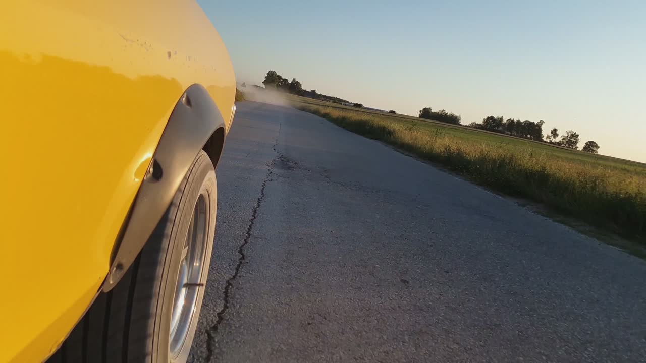 coches antiguos amarillos conducen por un polvoriento camino rural de grava