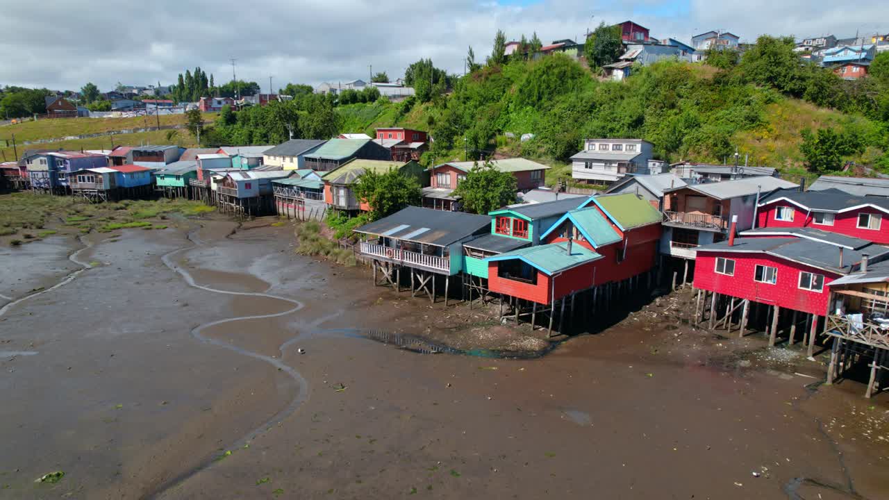 Dolly in flyover of the Castro stilt houses in Chiloé, low tide, low water level sunny day, Chile