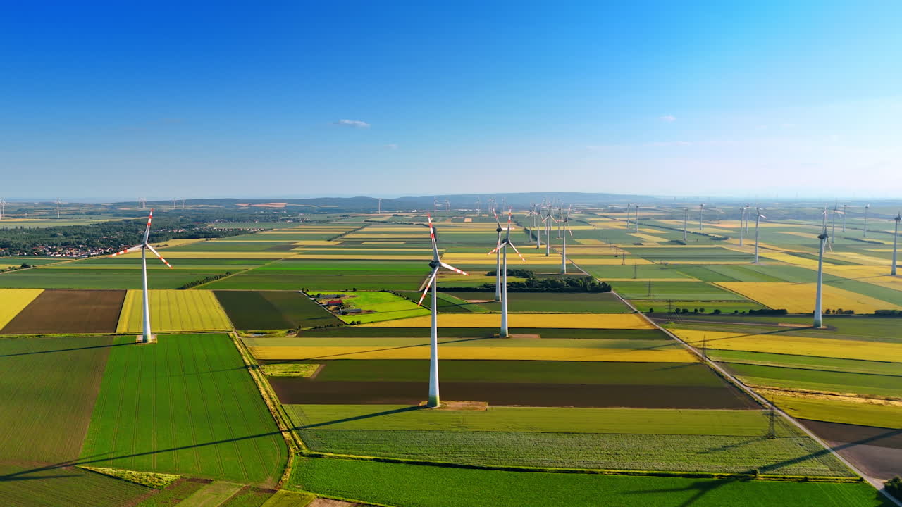 Green and yellow fields in the picturesque countryside. Wind turbines rotate in the wind. Aerial view.