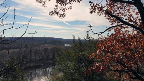 aerial view through autumn trees emptying out over a cliff with a river below