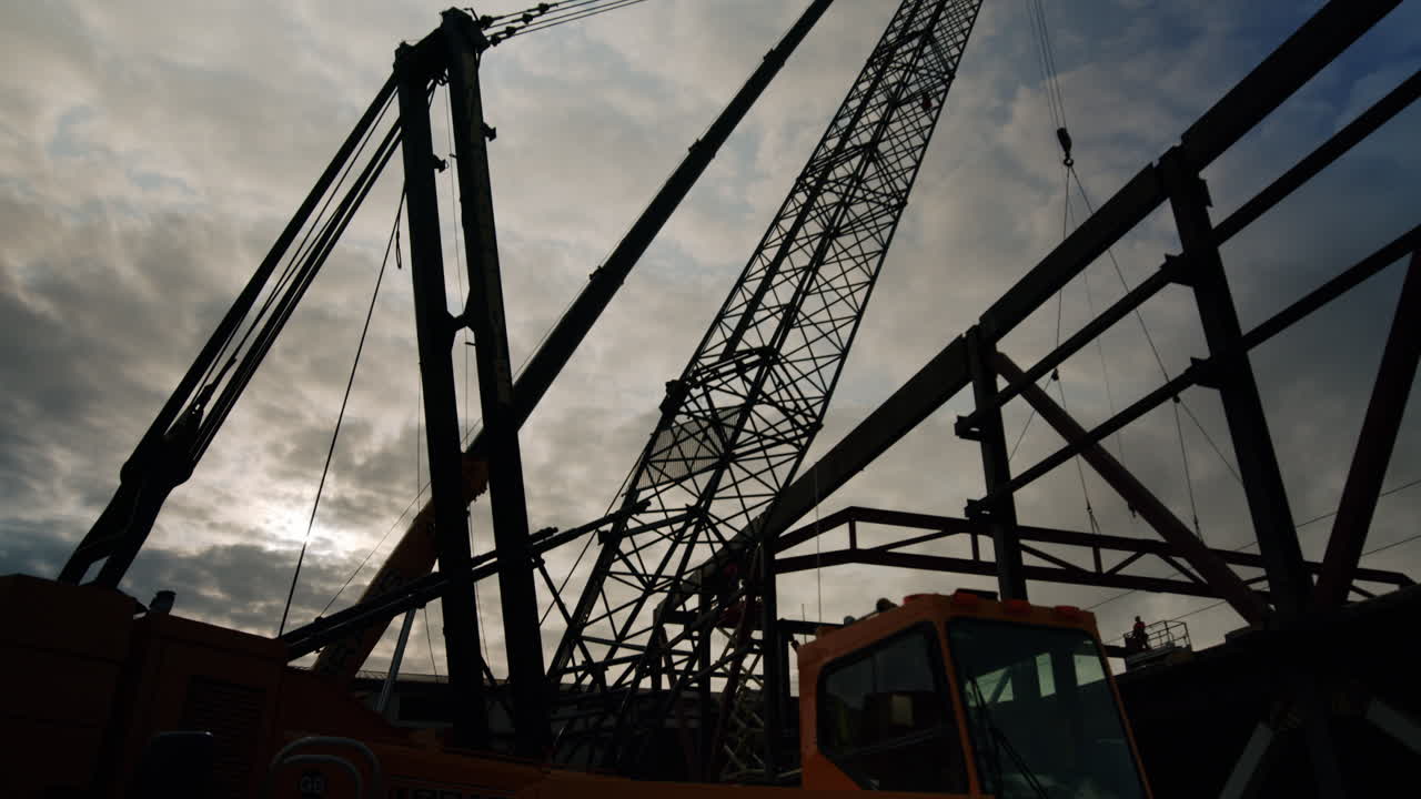 Silhouetted Cranes and Steel Construction Site