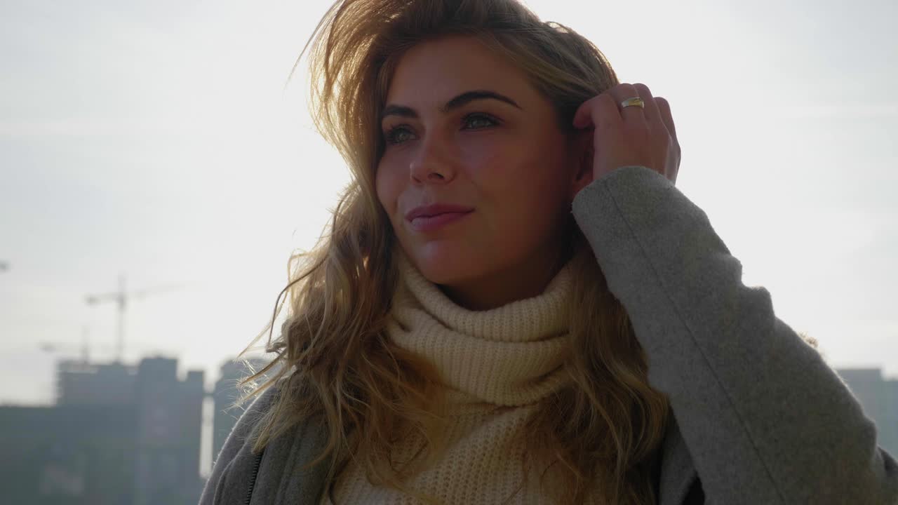 hermosa mujer de moda arregla el cabello y sonríe, recortada por el sol