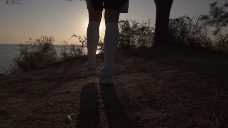 A-Silhouette-Of-A-Basketball-Player-Girl-Comes-With-A-Ball-In-Her-Hand,-Coming-Up-To-The-Slope-With-Trees-Around