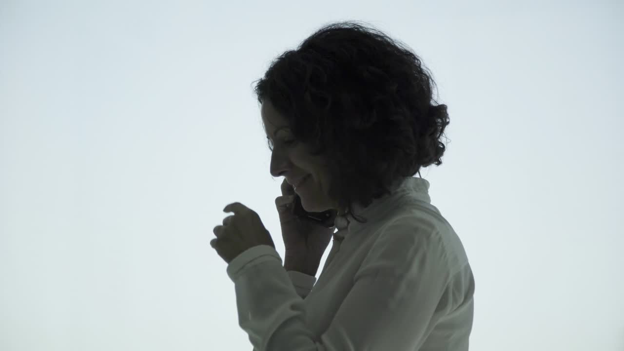 mujer de negocios alegre de mediana edad hablando por teléfono inteligente