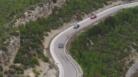 Vista-Aérea-Después-De-Tres-Coches-Valiosos-De-Gama-Alta-Que-Conducen-Rápido-A-Lo-Largo-De-Las-Carreteras-Sinuosas-Del-Bosque-De-Barcelona