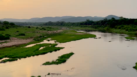 Kruger-National-Park-sunset-on-river-South-Gate-entrance-birds-flamingo-crocodile-below-rainy-spring-green-lush-stunning-mountainous-landscape-cinematic-iPhone-pan-to-the-left