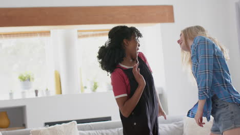 happy diverse teenage female friends dancing at home, slow motion