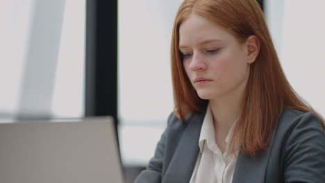young female accountant is working on modern office checking reports in laptop sending email by internet corporative chat