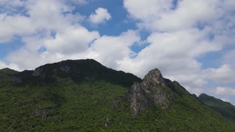 imágenes aéreas deslizantes hacia la izquierda que revelan esta majestuosa montaña de piedra caliza, hermosas nubes algodonosas, cielo azul