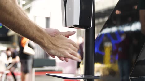 person washing hands at automatic soap dispenser