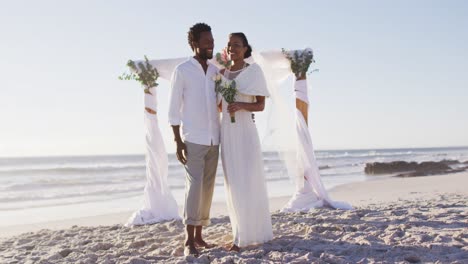 Porträt-Eines-Verliebten-Afroamerikanischen-Paares,-Das-Heiratet-Und-Am-Strand-In-Die-Kamera-Lächelt