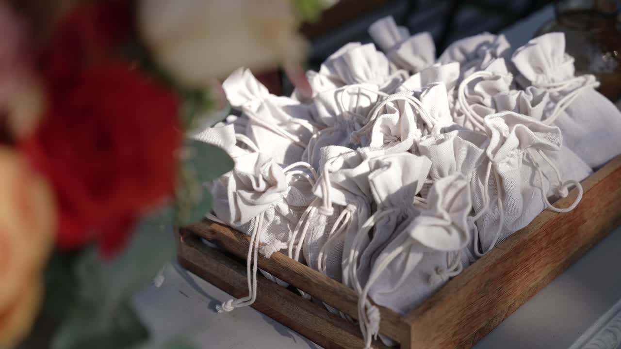 white fabric gift pouches neatly arranged in a wooden tray as rustic wedding favors