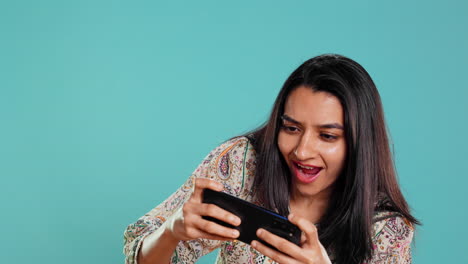 Happy-woman-playing-videogames-on-smartphone,-celebrating-after-win