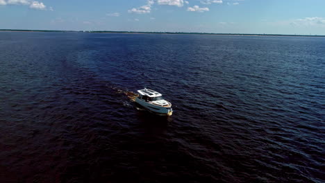 aerial drone shot of modern white motor boat along the horizon on dark water, drone at daytime