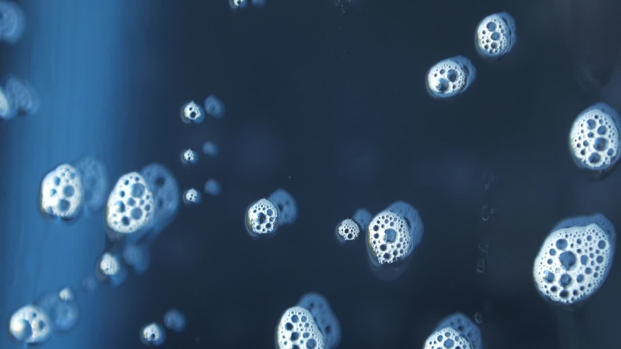 비누 거품의 매크로 사진, 창문 청소 화학, 유리 아래로 흐르는 아름다운 반사.