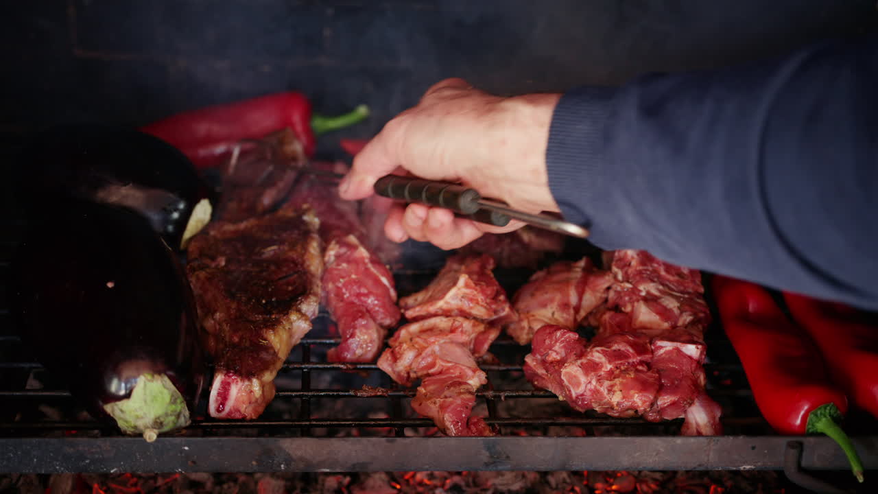 Daging panggang dengan bekas panggangan terlihat jelas sedang dibalik saat dimasak di atas bara api panas bersama sayuran.