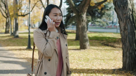 woman walking and talking on phone in autumn park