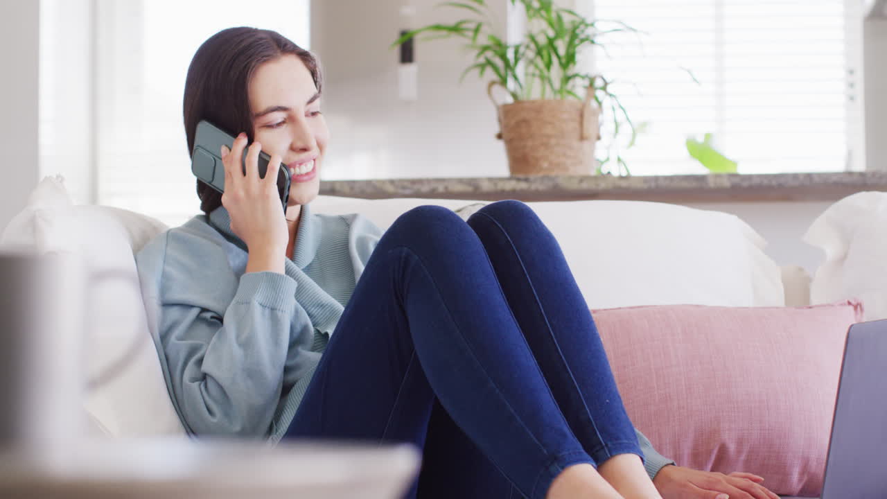 소파에 앉아 스마트폰으로 대화하는 행복한 백인 여성