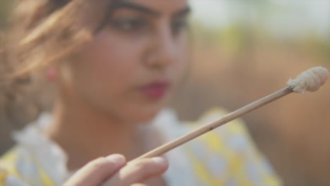 closeup shot of a young woman with a septum ring dabbing a brush unto a broken piece of clay pottery