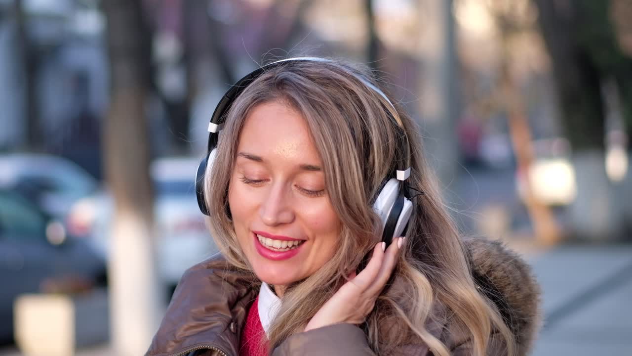 Woman listening to music in her headphones while singing along and dancing in the street