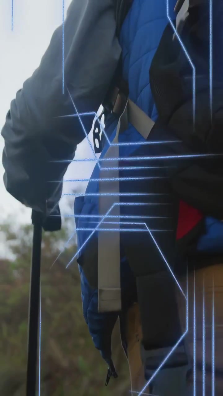 Video verticale: Mano su un bastone che inizia una panoramica, escursionista che sale in salita, linee tecnologiche pulsanti che attraversano l'escursionista.