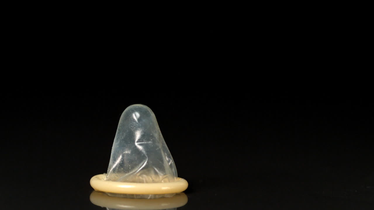 condón cayendo sobre un fondo negro