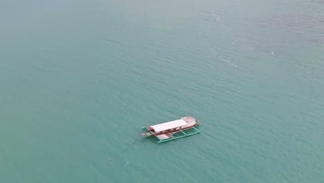 Schöne-Luftdrohnenaufnahme-Eines-Fischerbootes,-Das-In-Der-Nähe-Des-Küstenstrandes-Von-Puerto-Galera,-Philippinen,-Verankert-Ist