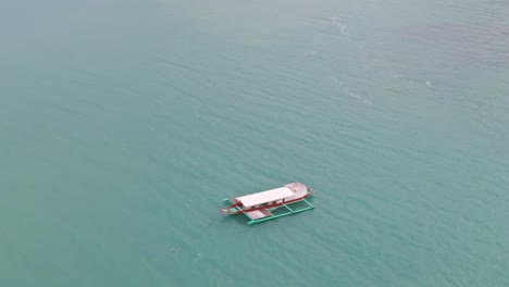 nice aerial drone shot of fishing boat anchored off near at shoreline beach of puerto galera, philippines