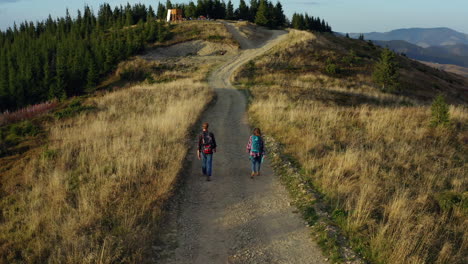 Aerial-couple-trekking-road-on-mountains-enjoying-time-warm-spring-morning