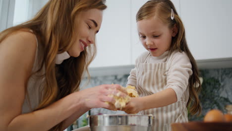 Schöne-Frau-Und-Tochter-Beim-Kochen-In-Der-Küche.-Mutter-Nimmt-Gebäck-Aus-Den-Händen-Des-Kindes