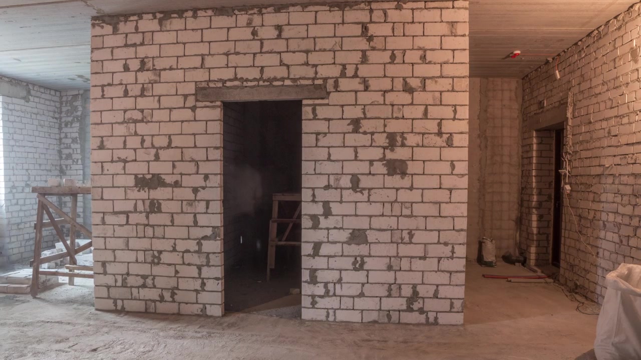 Builders laying brick walls inside appartment with professional tools timelapse. Workmen at work, bricklayers building wall, contractor and worker. Building materials around