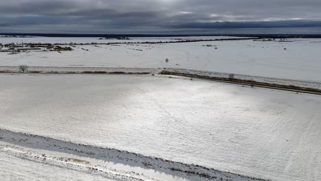 Drone-video-of-beam-of-sunlight-piercing-through-the-winter-clouds-and-illuminating-a-snow-covered-field