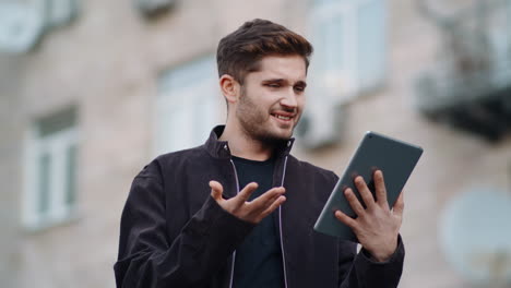 Surprised man looking tablet screen outside. Cheerful guy reading message tablet