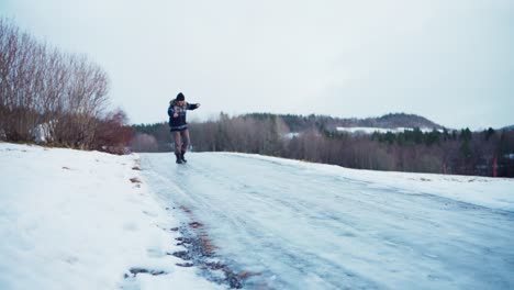 A-Man-is-Attempting-to-Walk-on-a-Slippery,-Icy-Road---Static-Shot