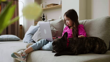 女の子が家で犬を撫でている