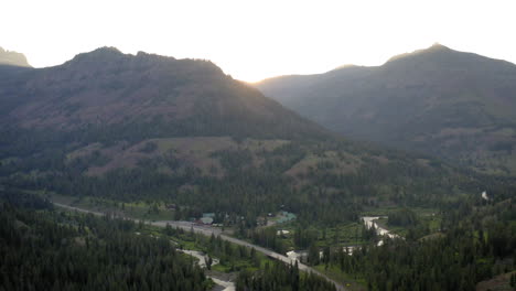 mountain valley landscape with road, river, and lodge at sunrise or sunset