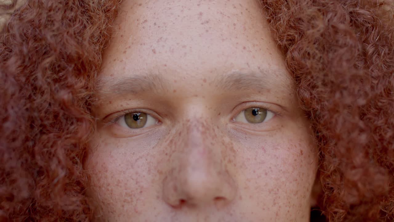 retrato de un hombre caucásico con cabello rojo y pecas sonriendo, en cámara lenta
