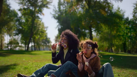 family blowing air bubbles enjoying warm spring day park. mother day celebration